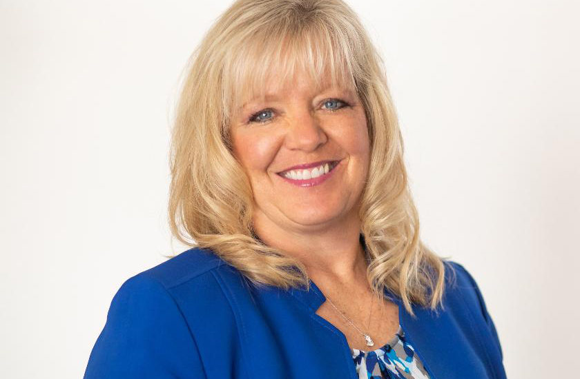 Woman smiling in a blue suit smiling.