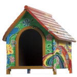 A cute doghouse painted in bright colors with flowers and a rainbow.