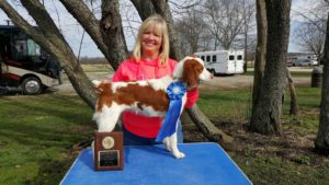 Dog owner with her dog and the blue ribbon she just won.