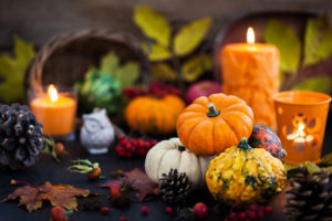 Autumnal colorful pumpkins and fallen leaves with two lit candles.