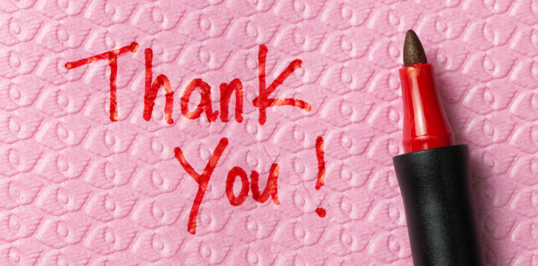 Thank you written in red pen on a bright pink napkin.