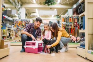 Family buying supplies for little puppy in petshop. Father, mother and daughter chooses accessories for dog in pet shop